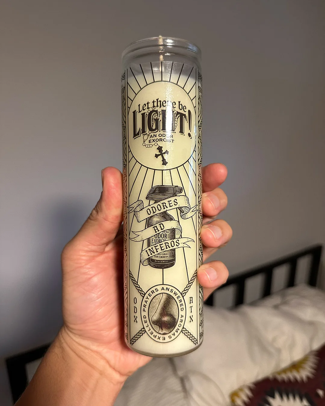 A large, 12 oz sprayer candle from Odor Exorcism being held in a hand.
